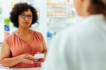 women holding her prescription medication in a pharmacy