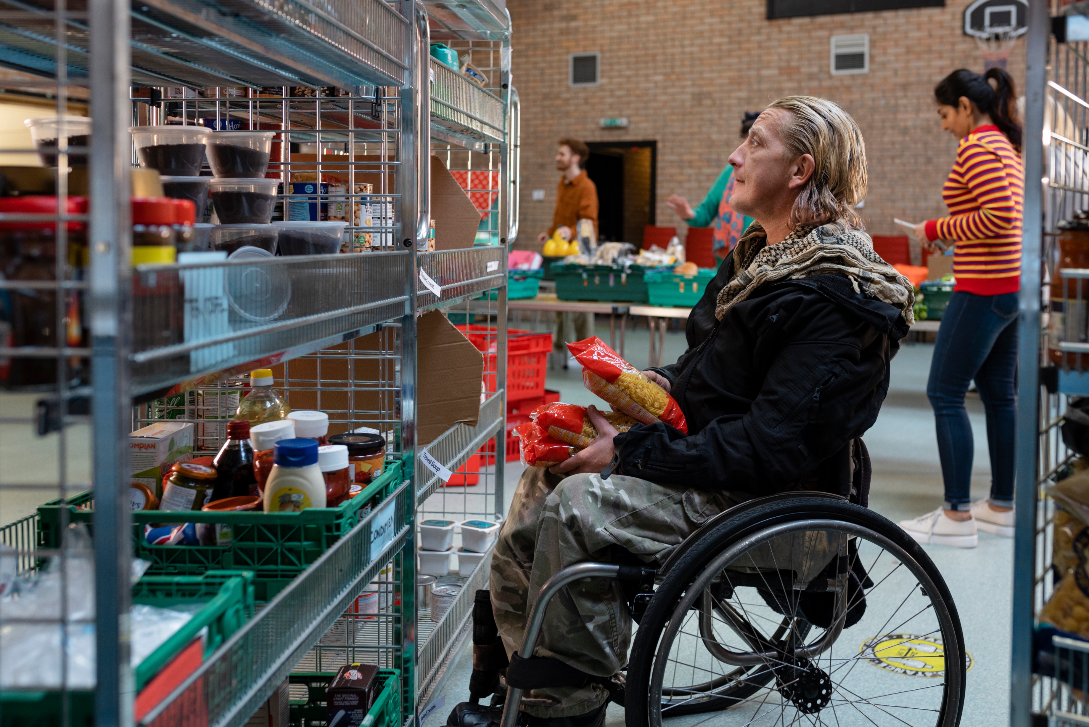 Male in wheelchair looking at foodbank shelves