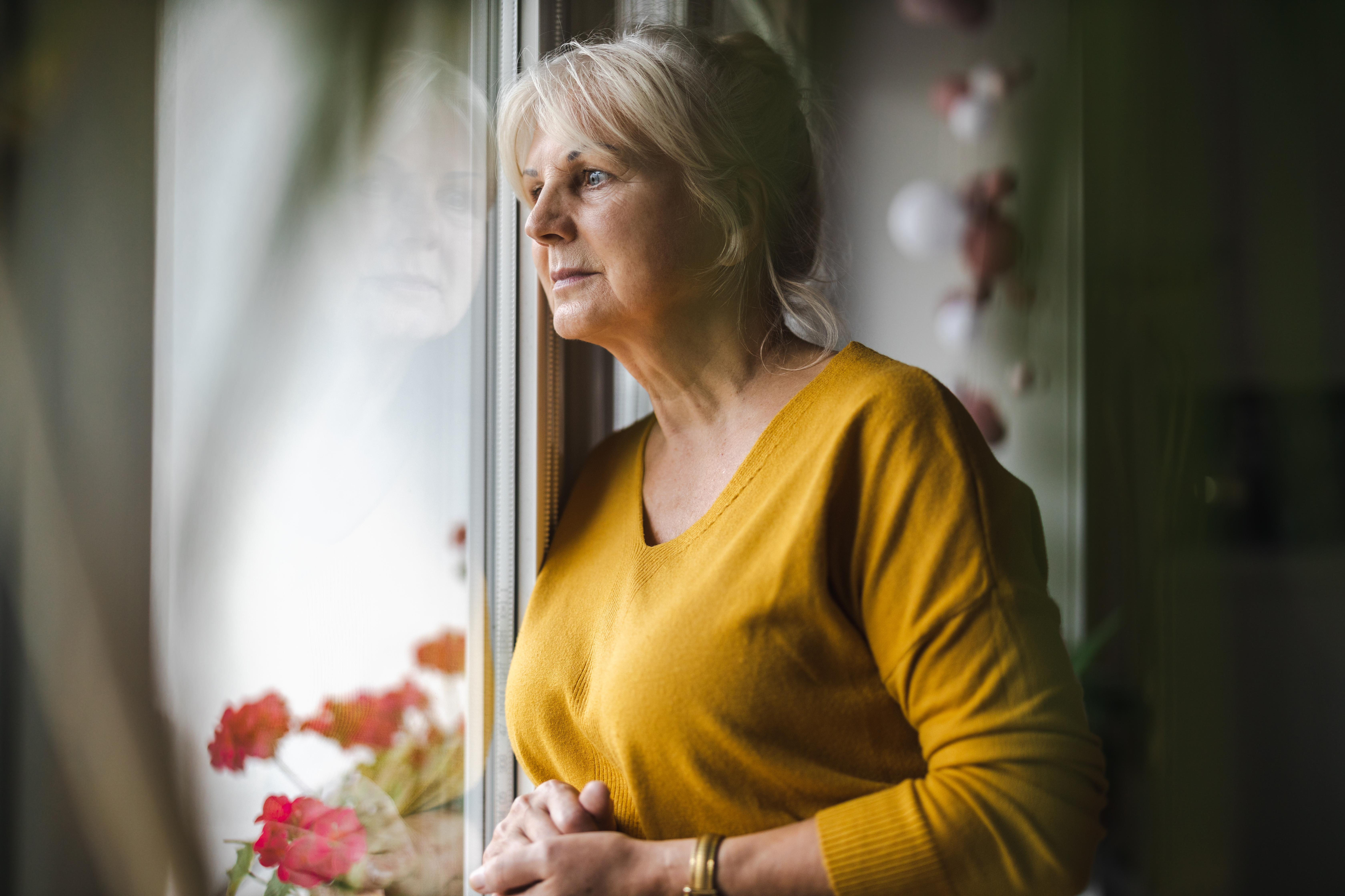 Woman stood and looking out of her window