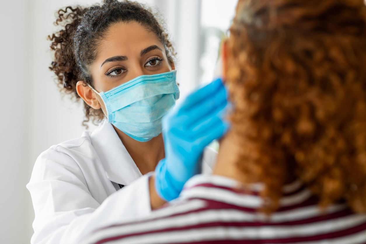 nurse with facemask examining a woman