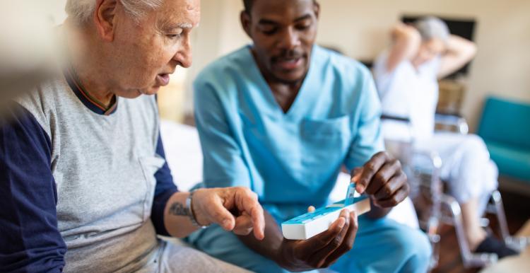 nurse sat next to male patient on bed