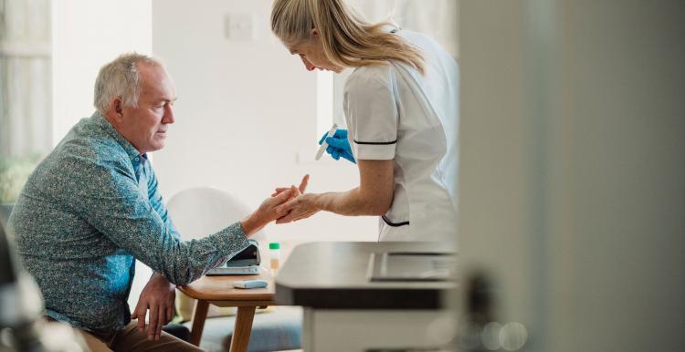 Nurse doing diabetes finger prick check for male patient