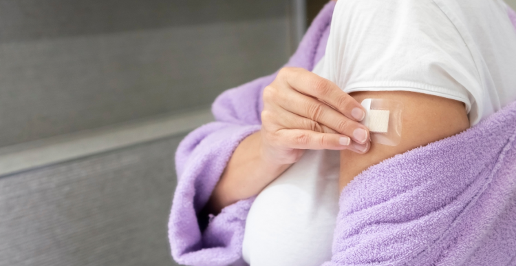 woman in dressing gown putting HRT patch on arm