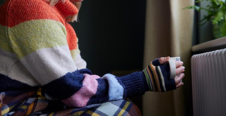 Woman in gloves holding hot drink to stay warm 