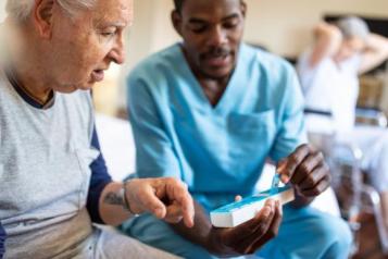 nurse sat next to male patient on bed