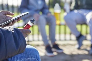 three teens in park, one is holding a vape in their hand