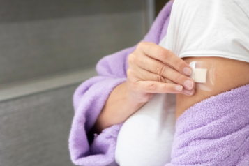 woman in dressing gown putting HRT patch on arm