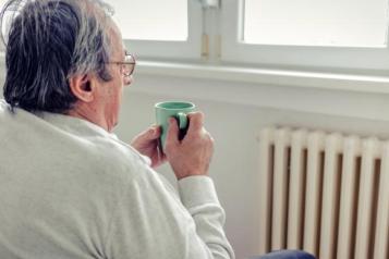 Man with cup of tea looking outside his window