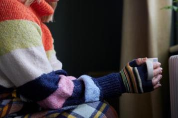 Woman in gloves holding hot drink to stay warm 