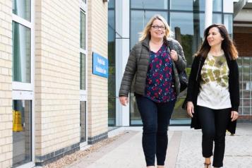 Two women walking outside a hospital