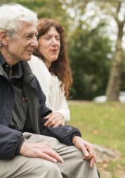 Elderly person sitting on a bench with a friend.